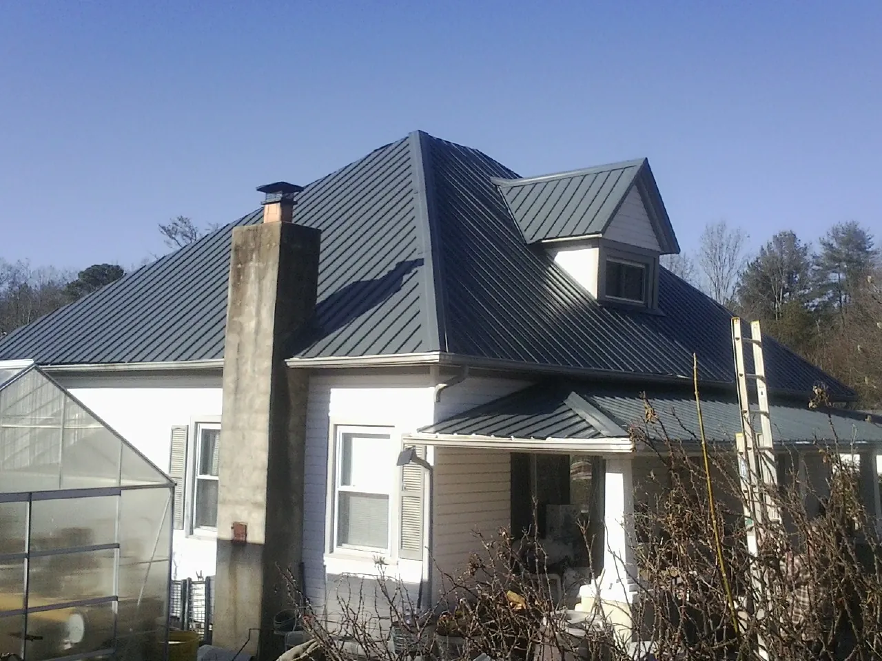 Dark blue standing seam metal roof on a white farmhouse with dormer — Slate & Tile Roof Repair by Roofing Brothers in Orland