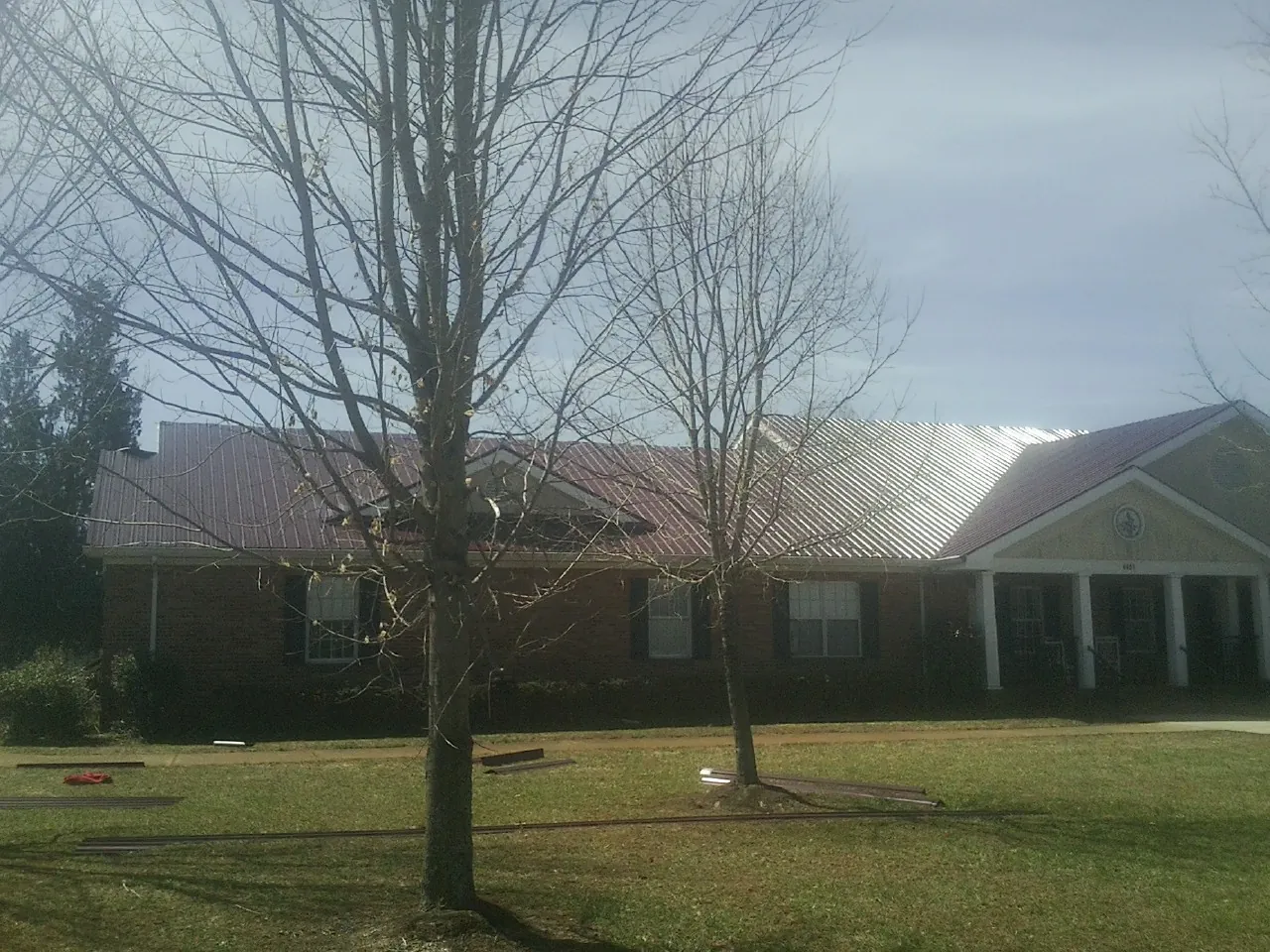 Red metal roof on a brick building seen from the front lawn in Orland
