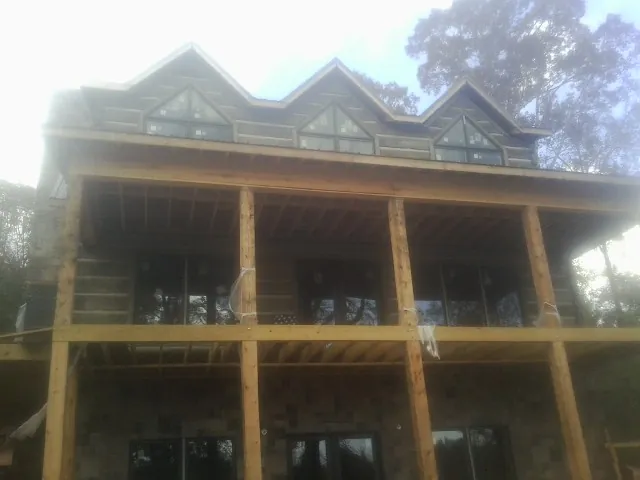 Dormers and porch framing on a large log home under construction — Roof Coating work by our crew in Orland