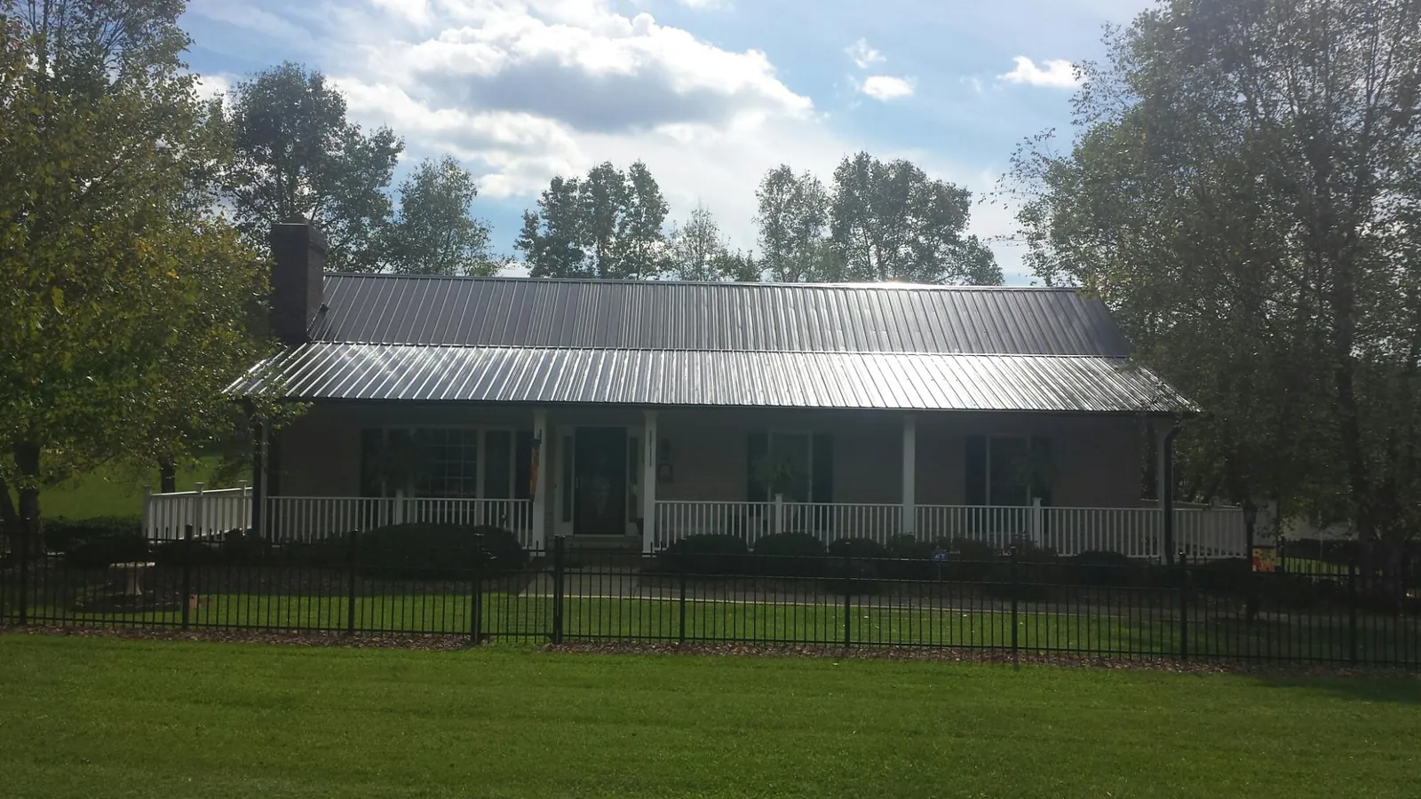 Gray metal roof on a brick ranch with a full width front porch — Gutter Guard Installation work by our crew in Orland