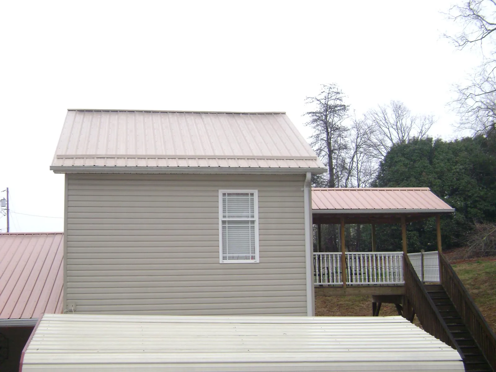 Tan metal roofs on a two story addition and attached porch, from a Roof Replacement job in Orland